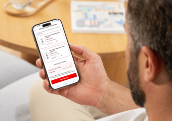 Pessoa segurando um smartphone com uma aplicação aberta exibindo informações e botões vermelhos.